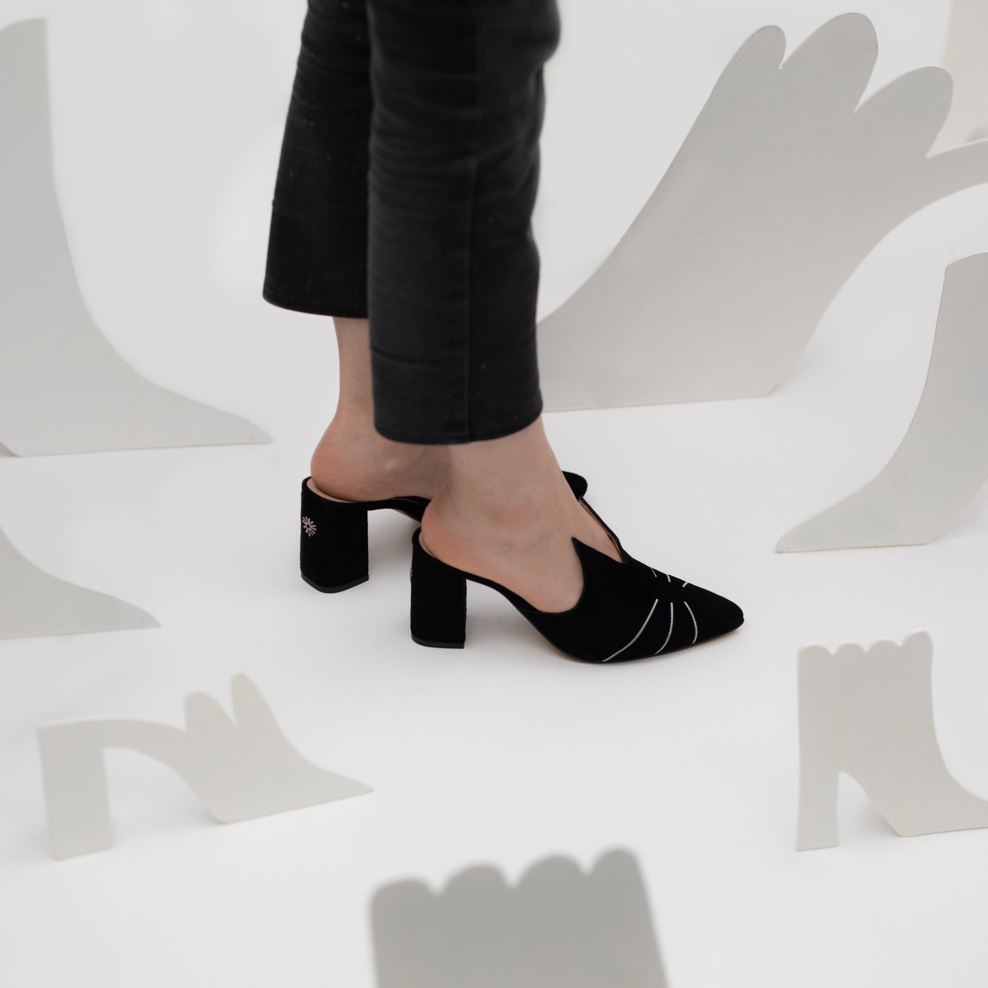 Timeless black suede cat mules embroidered with silver whiskers and a pointed toe and cat ears.