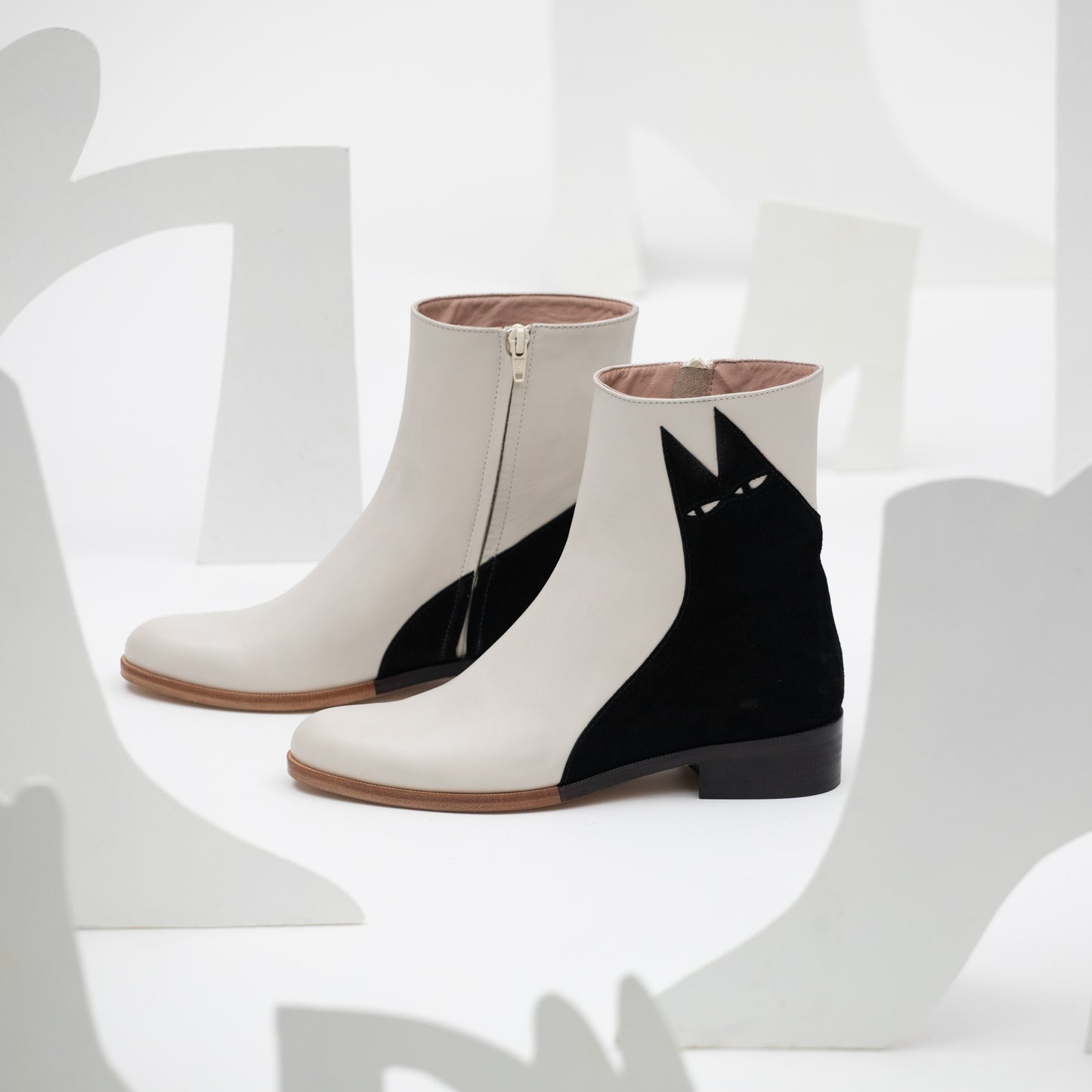 Artistic shot of the low Ziggy cat boot in a white setting with stylised cut out shoe illustrations.