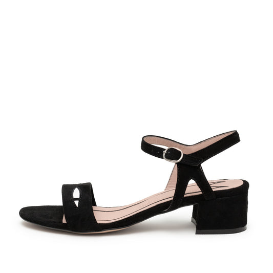 A black suede opened toed sandal with cat eyes on the toe strap. Lined with pink leather the ankle straps have a metal clasp.